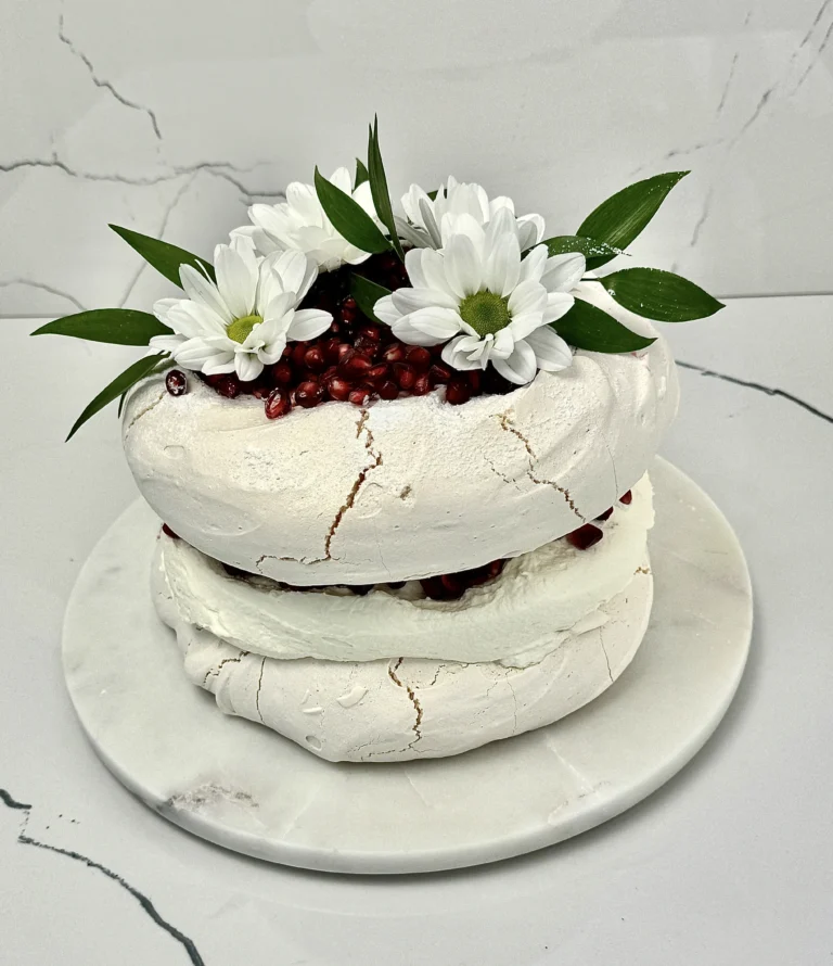 Zdjęcie przedstawia tort bezowy z granatem możliwy do zamówienia przez sklep cukierni Bezownia znajdującej się w Warszawie, ul. F. Joliot-Curie 11