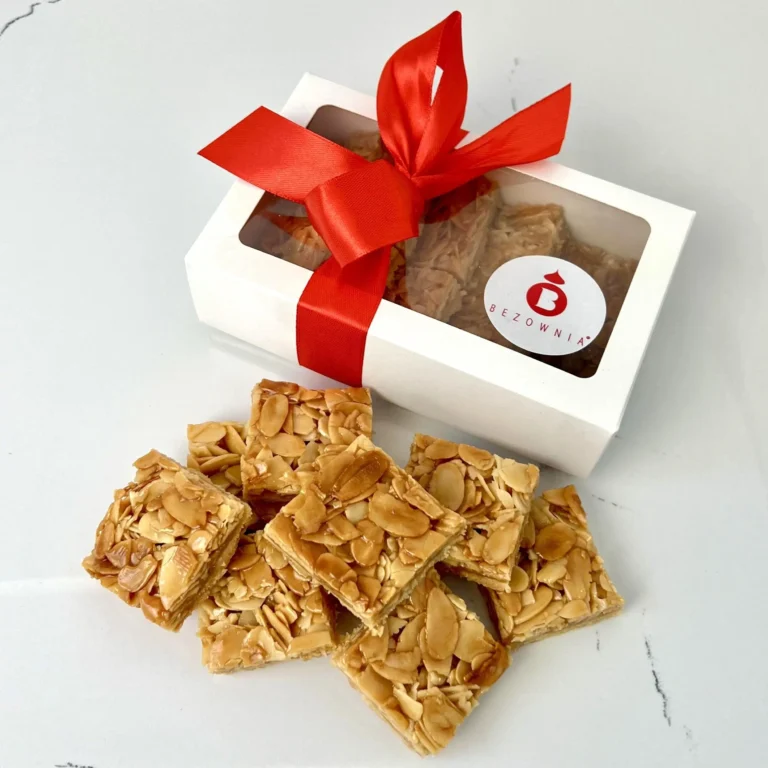 Zdjęcie przedstawia gotowy zestaw do zakupu - ciasteczka florentynki w białym opakowaniu przewiązane czerwoną kokardką w 5 smakach - możliwy do zamówienia przez sklep cukierni Bezownia znajdującej się w Warszawie, ul. F. Joliot-Curie 11