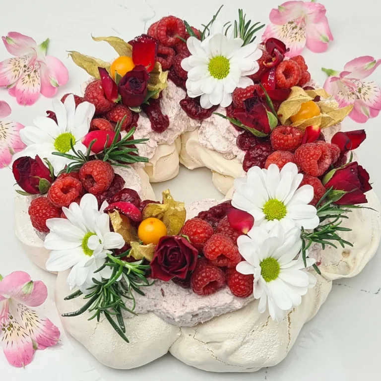 Zdjęcie przedstawia TORT BEZOWY PAVLOVA z kremem różanym i musem malinowym - możliwy do zamówienia przez sklep cukierni Bezownia znajdującej się w Warszawie, ul. F. Joliot-Curie 11