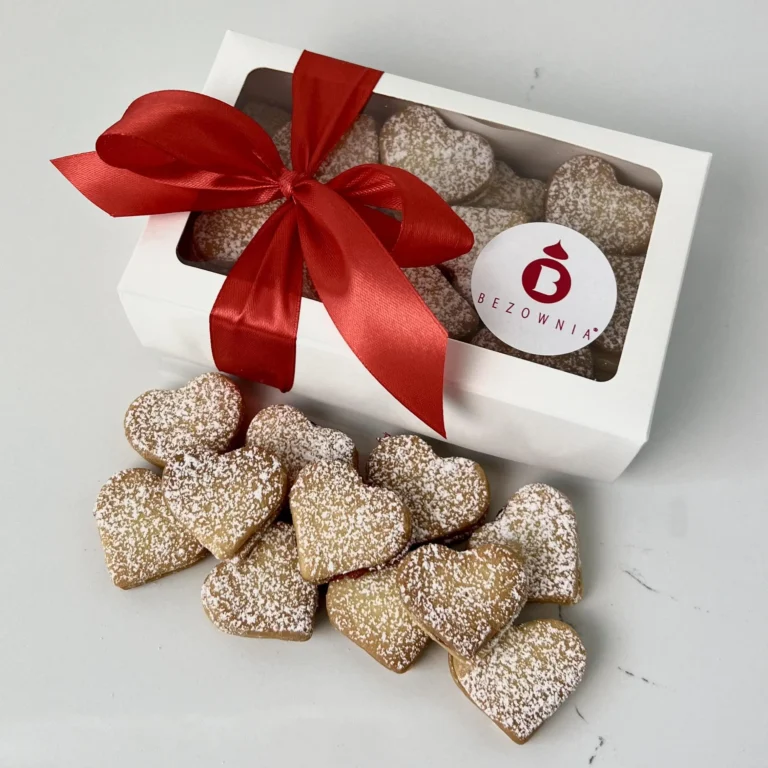 Zdjęcie przedstawia gotowy zestaw do zakupu - Serduszka z konfiturą z płatków róży w białym opakowaniu przewiązane czerwoną kokardką w 5 smakach - możliwy do zamówienia przez sklep cukierni Bezownia znajdującej się w Warszawie, ul. F. Joliot-Curie 11