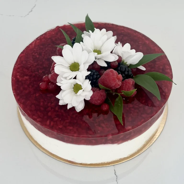 Zdjęcie przedstawia sernik na zimno z galaretką i owocami możliwy do zamówienia przez sklep cukierni Bezownia znajdującej się w Warszawie, ul. F. Joliot-Curie 11