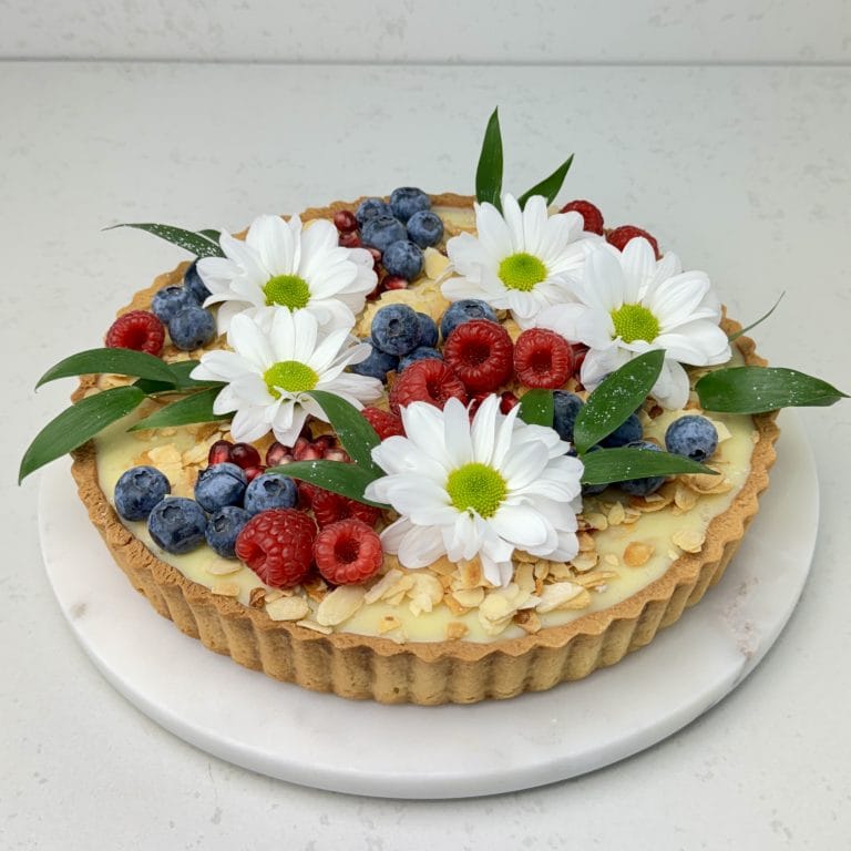 Zdjęcie tarty z białą czekoladą i czarną porzeczką - możliwa do zamówienia przez sklep cukierni Bezownia znajdującej się w Warszawie, ul. F. Joliot-Curie 11