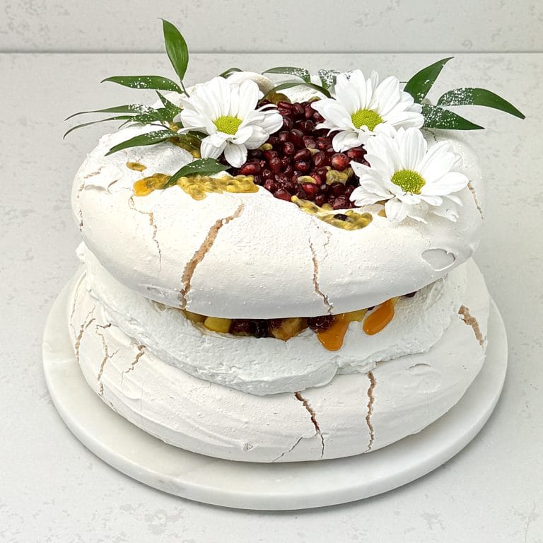 Zdjęcie przedstawia tort bezowy mango granat marakuja możliwy do zamówienia przez sklep cukierni Bezownia znajdującej się w Warszawie, ul. F. Joliot-Curie 11