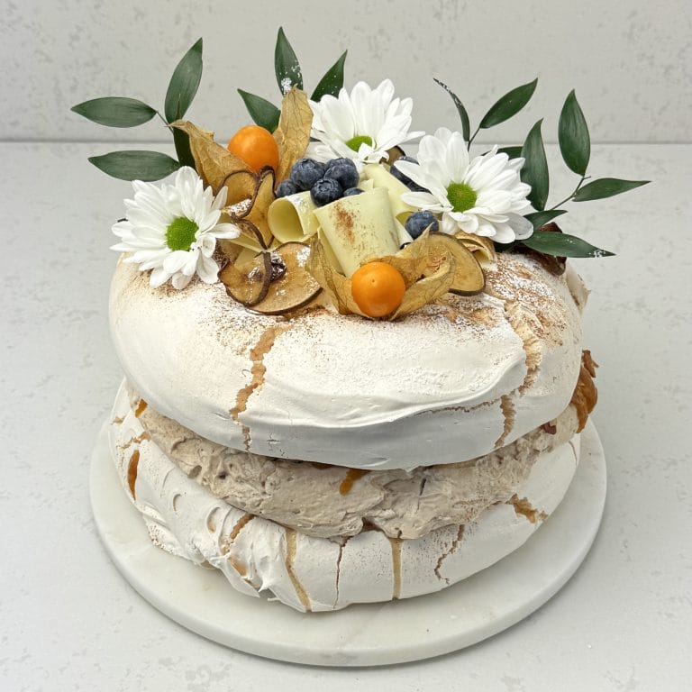 Zdjęcie przedstawia tort bezowy z karmelizowaną gruszką i orzechami włoskimi - możliwy do zamówienia przez sklep cukierni Bezownia znajdującej się w Warszawie, ul. F. Joliot-Curie 11.