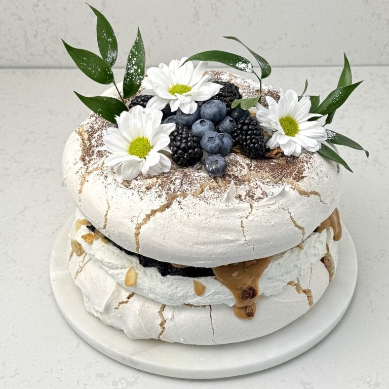 Zdjęcie przedstawia tort bezowy kajmakowo-porzeczkowy możliwy do zamówienia przez sklep cukierni Bezownia znajdującej się w Warszawie, ul. F. Joliot-Curie 11