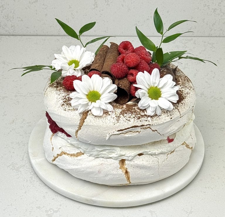 Zdjęcie przedstawia tort bezowy malinowy-możliwy do zamówienia przez sklep cukierni Bezownia znajdującej się w Warszawie, ul. F. Joliot-Curie 11