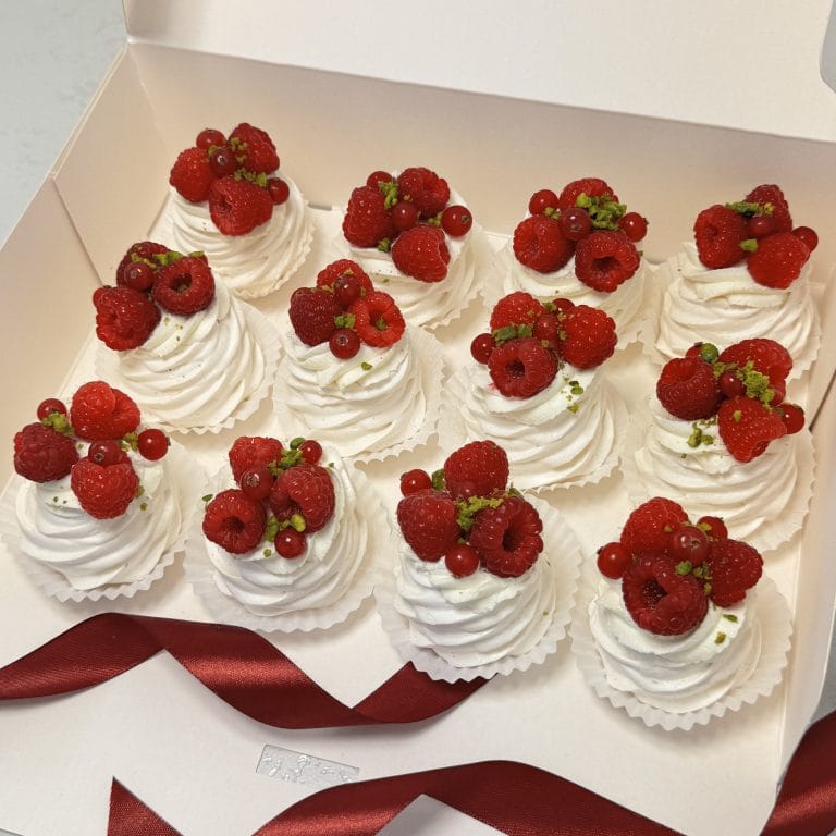 Zdjęcie przedstawia 12 bezików, które są udekorowane świeżymi owocami. Beziki można zamawiać przez sklep cukierni Bezownia znajdującej się w Warszawie przy ul. Joliot-Curie 11.