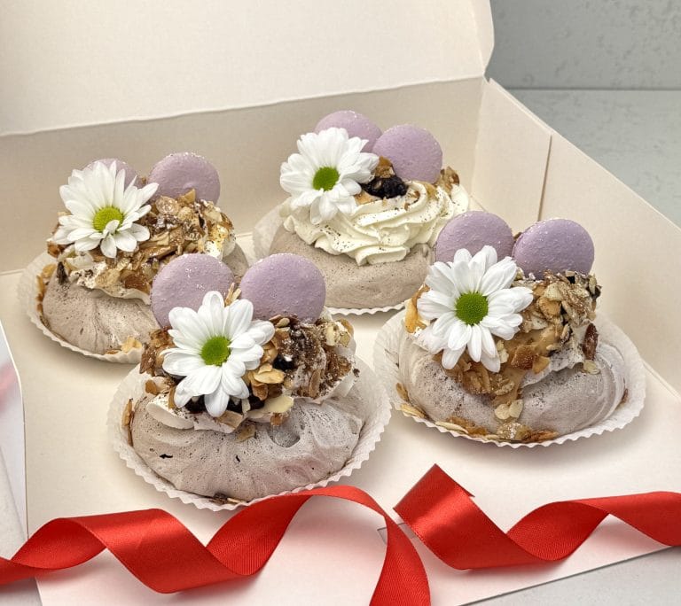 Zdjęcie przedstawia 4 beziki mini Pavlova z musem z czarnej porzeczki, kajmakiem, migdałami, udekorowane świeżymi kwiatami - możliwe do zamówienia przez sklep cukierni Bezownia znajdującej si