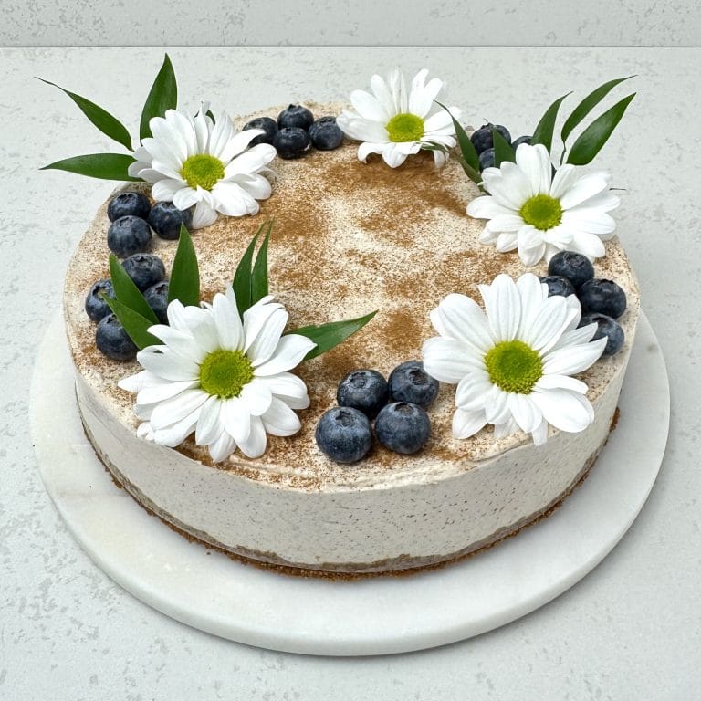 Zdjęcie przedstawia okrągły sernik na zimno cynamonem i pierniczkami. Sernik możliwy jest do zamówienia przez sklep cukierni Bezownia znajdującej się w Warszawie, ul. F. Joliot-Curie 11.