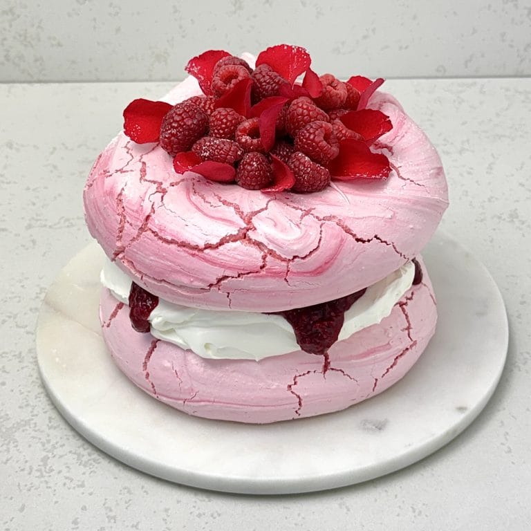 Zdjęcie przedstawia tort bezowy z musem malinowym, przygotowany na Walentynki. Tort można zamówić przez sklep cukierni Bezownia znajdującej się w Warszawie, ul. F. Joliot-Curie 11.