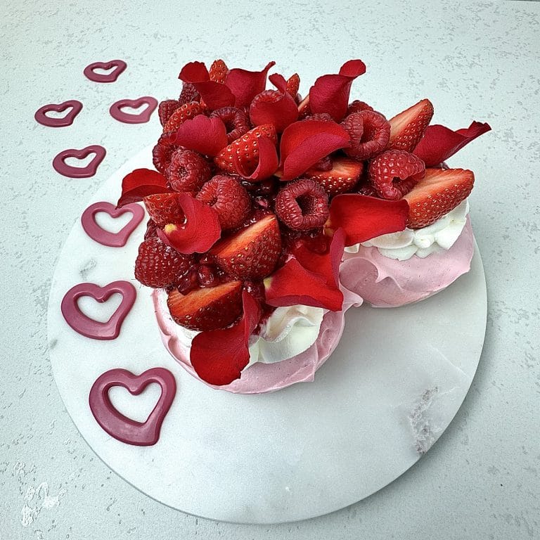 Zdjęcie przedstawia tort bezowy na Walentynki w kształcie serca. Tort można zamówić przez sklep cukierni Bezownia znajdującej się w Warszawie, ul. F. Joliot-Curie 11.